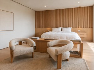 Cream upholstered chairs in a modern bedroom with a wooden bed and neutral rug