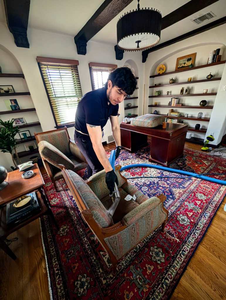 Delicate furniture cleaning on an upholstered wooden armchair with an extraction tool