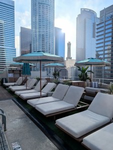Hotel rooftop lounge with upholstered chaise seating and umbrellas